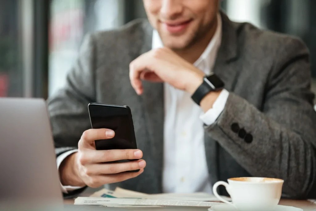 cropped image happy businessman sitting by table cafe using smartphone min